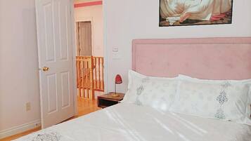 Un dormitorio con cama, un cuadro, una puerta y una escalera.