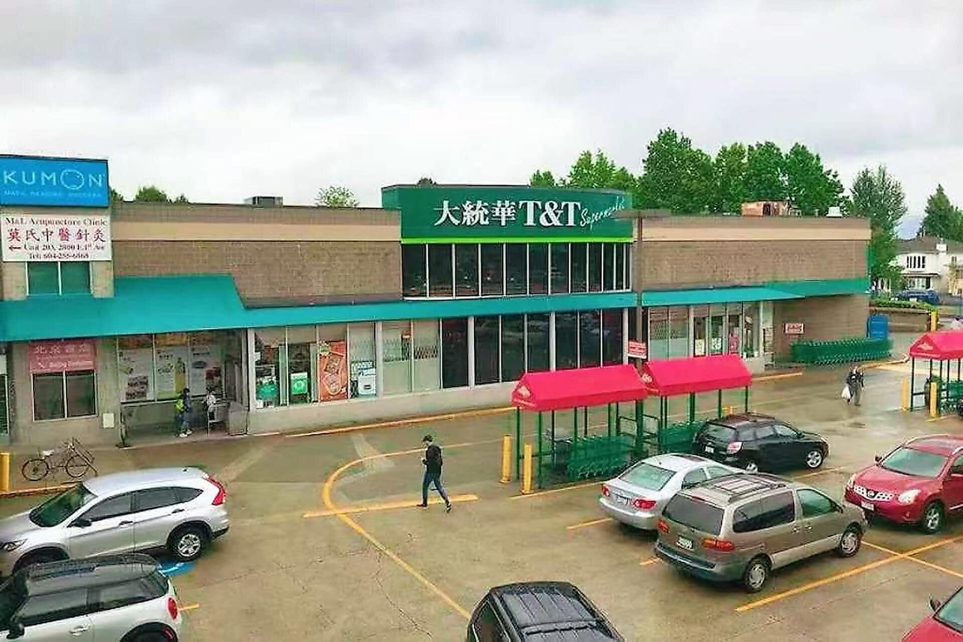 Una tienda T&T con toldo verde y un letrero en un idioma extranjero.