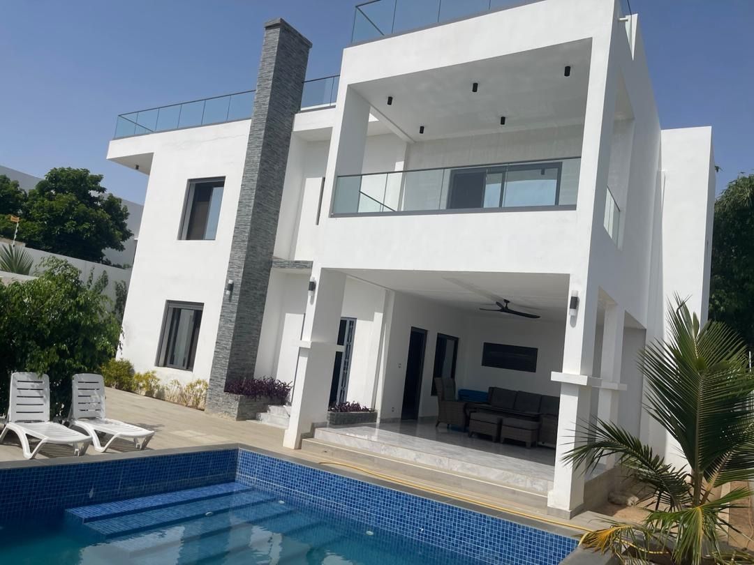 A modern two-story house with a swimming pool, outdoor seating, and a balcony.