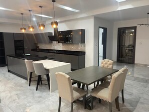 A modern kitchen with a central island, dark cabinetry, and pendant lighting.