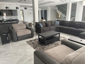 A modern living room with a sectional sofa, a leather armchair, and a coffee table.