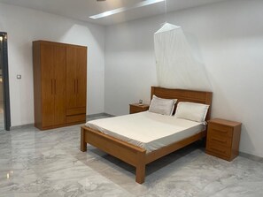 A bedroom with a wooden bed, nightstands, a wardrobe, and a mosquito net.
