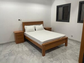Un dormitorio con una cama de madera, dos mesitas de noche y una ventana con persianas.