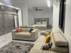 A bedroom with a bed, a sofa, a ceiling fan, and a wardrobe.