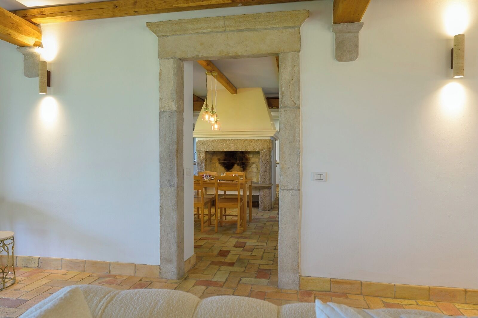 A room with a stone fireplace, wooden furniture, and a tiled floor.