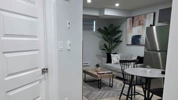 A modern kitchen with a dining area, white cabinetry, and a large plant.