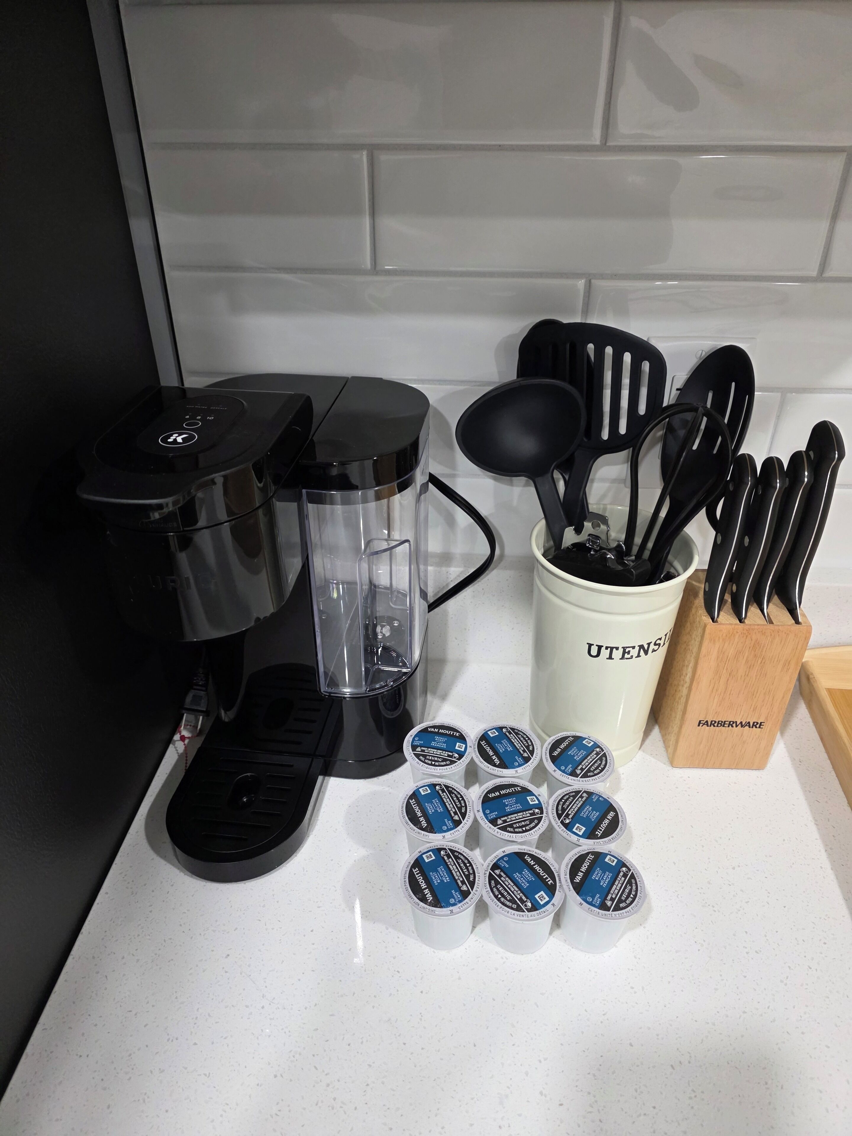 Een aanrecht met een koffiezetapparaat, een blender, een houder voor keukengerei en verschillende bakjes met Van Houten yoghurt.