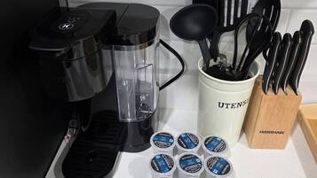 Een aanrecht met een koffiezetapparaat, een blender, een houder voor keukengerei en verschillende bakjes met Van Houten yoghurt.