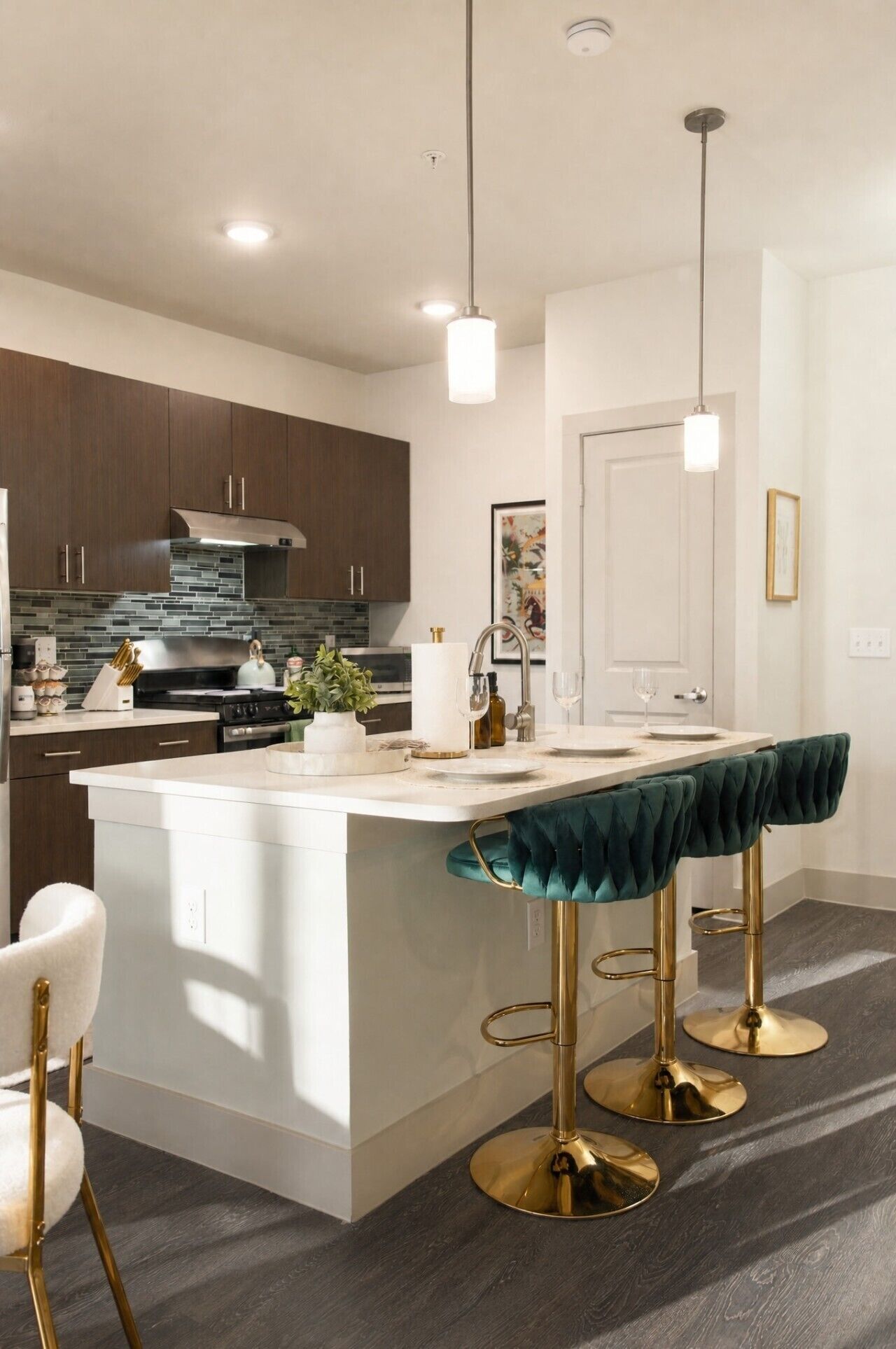 A modern kitchen with a central island, bar stools, and pendant lighting.