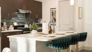 A modern kitchen with a central island, bar stools, and pendant lighting.
