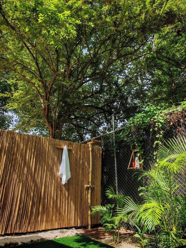 A bamboo fence, a white towel hanging on a hook, and a small wooden structure with a basket.