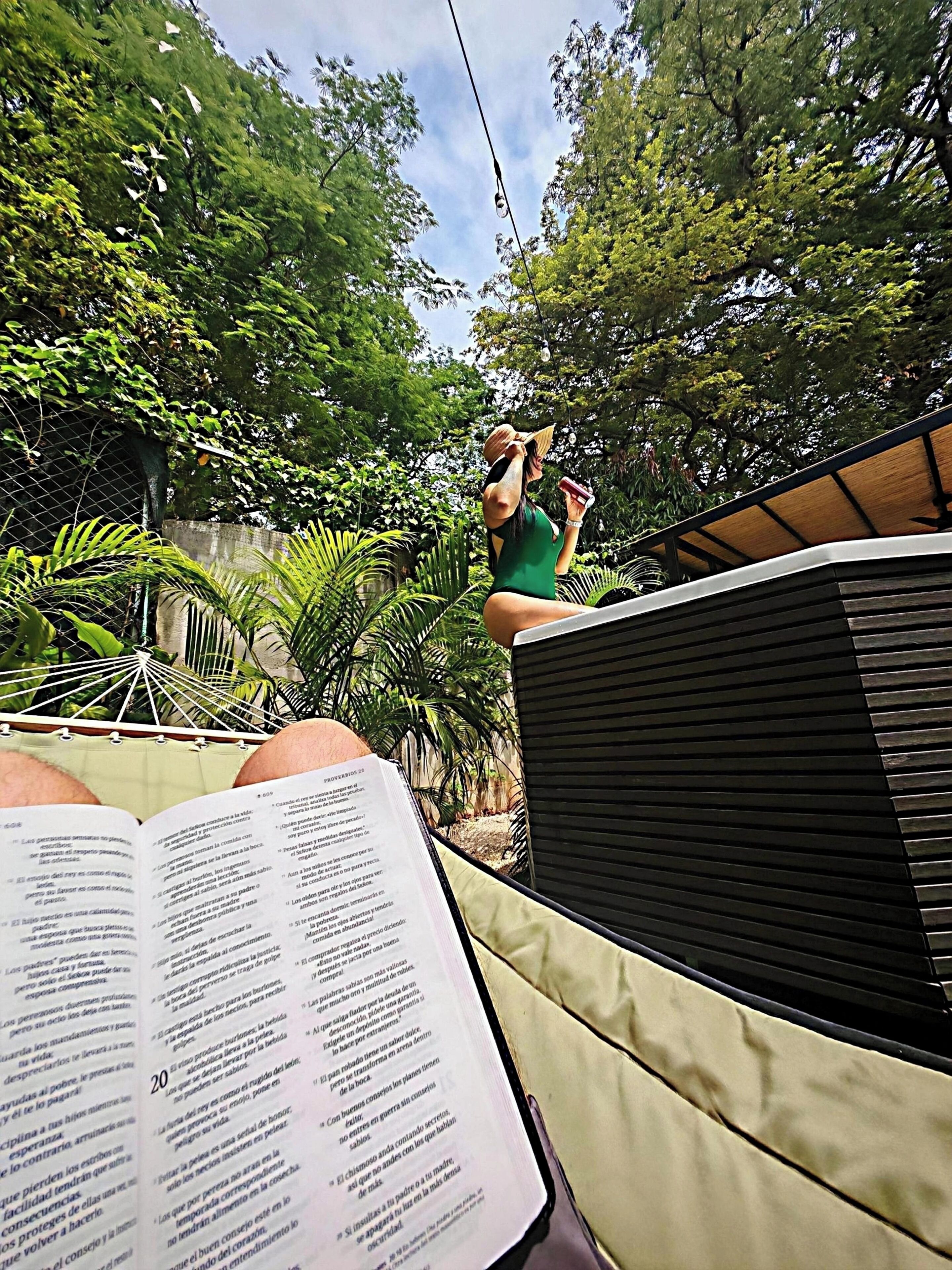 A hammock with a book and a person reading.