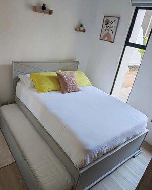 A bed with a headboard, a mattress, and pillows. There is a window with a view of the outside.