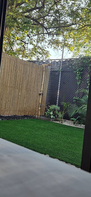 A fenced garden area with artificial grass and a bamboo fence.