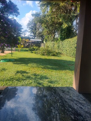 A view of a well-maintained garden with a lawn, trees, and a fence.