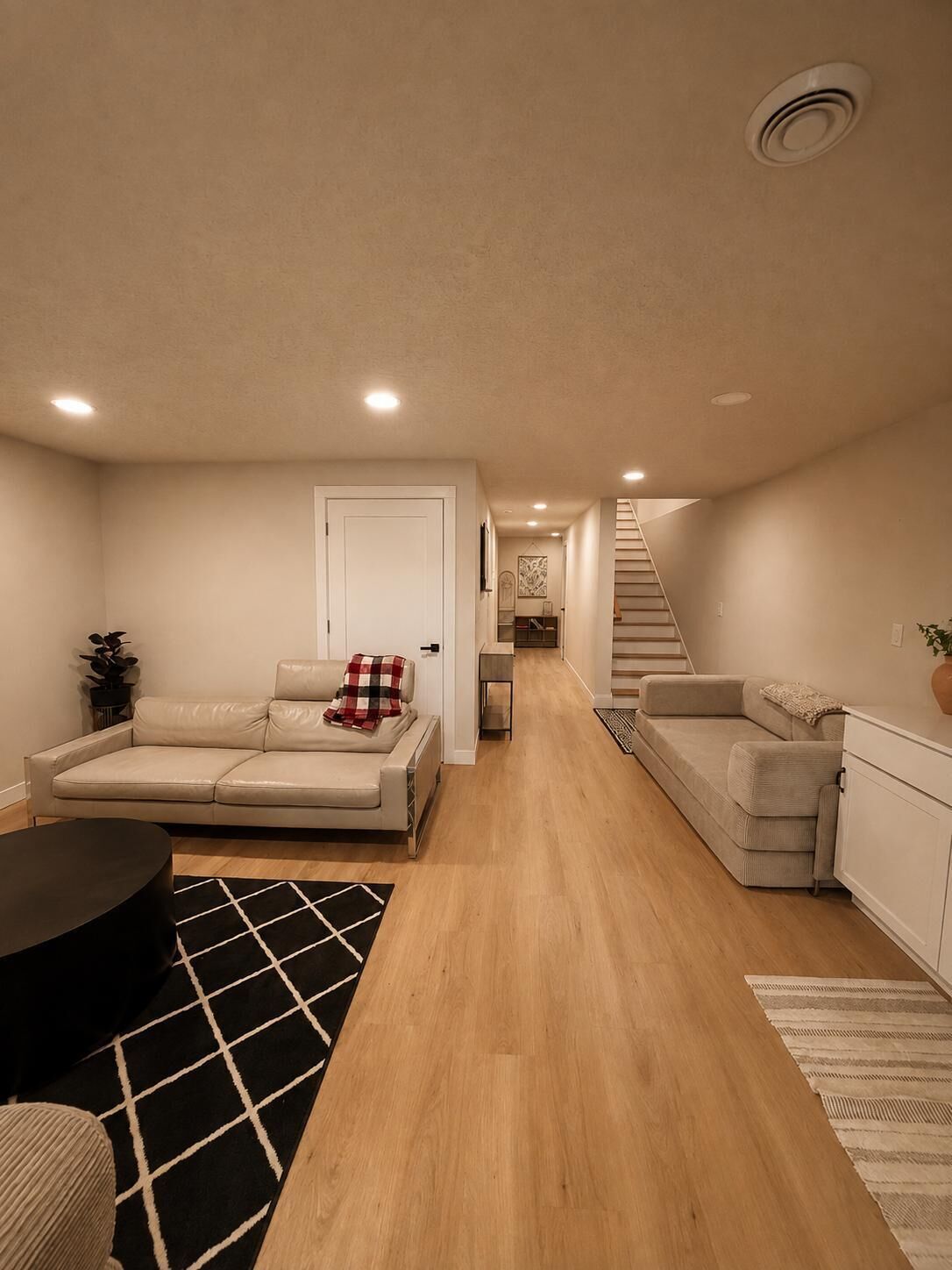 A modern living room with a sofa, a coffee table, and a staircase leading to another level.