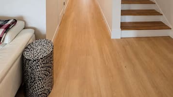 A hallway with a wooden floor, a staircase, and a door at the end.