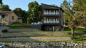 Et toetagers hus med en balkon, en støttemur og et vandareal i forgrunden.