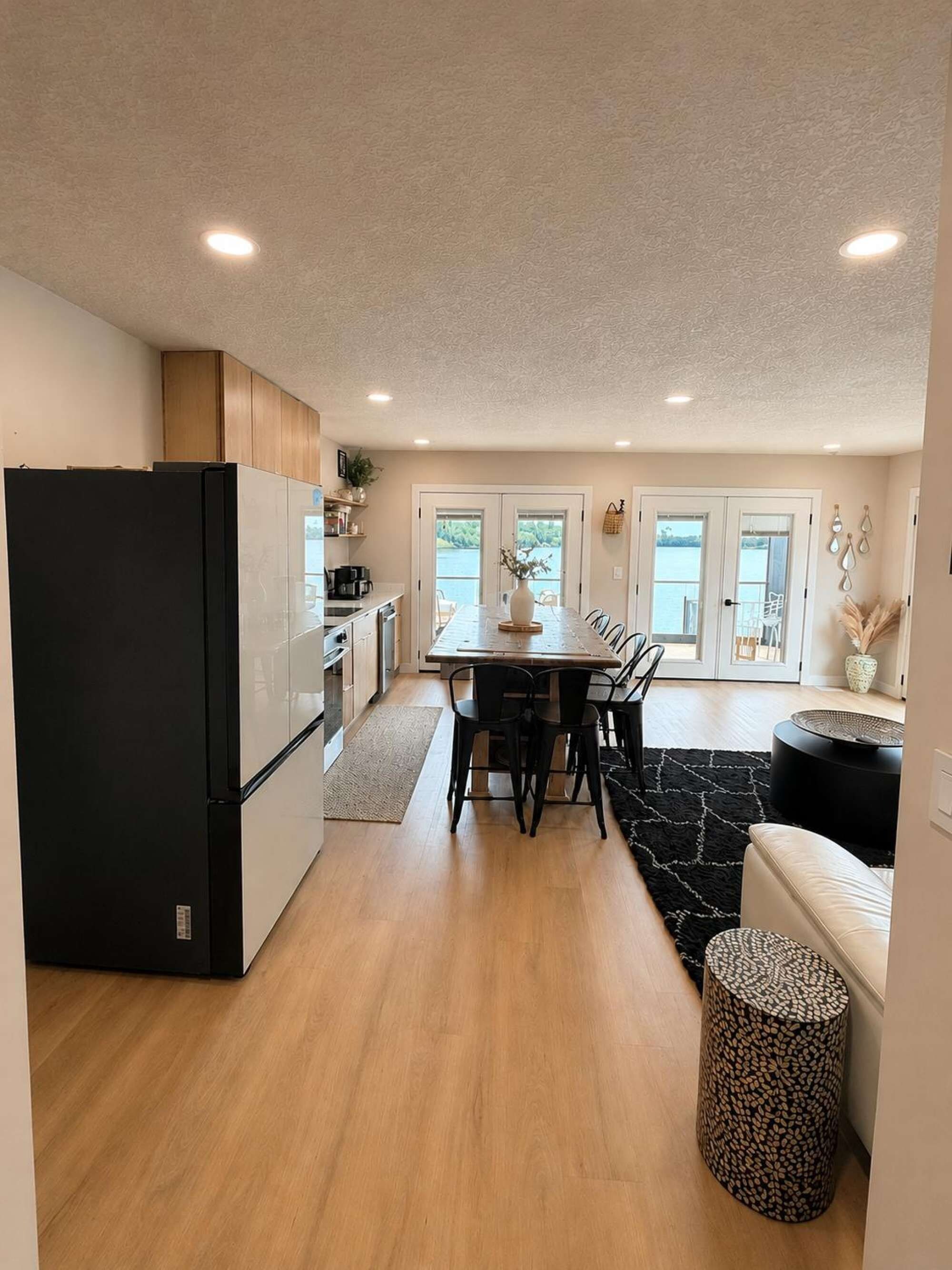 A modern kitchen with a dining area, wooden cabinets, and a black refrigerator.