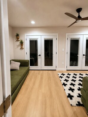 Une pièce avec un canapé vert, un tapis à motifs et un ventilateur de plafond.
