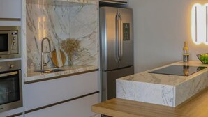 Una cocina moderna con horno integrado, refrigerador de acero inoxidable y una salpicadura de mármol.