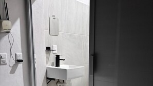 A modern bathroom with a white sink, a toilet, and a trash bin. - Cozy 1-bedroom studio in soothing Quimixto with AC (Quimixto)