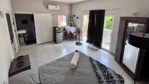 A compact room with a bed, a small kitchenette, a dining area, and a sliding door leading to a balcony. - Cozy 1-bedroom studio in soothing Quimixto with AC (Quimixto)