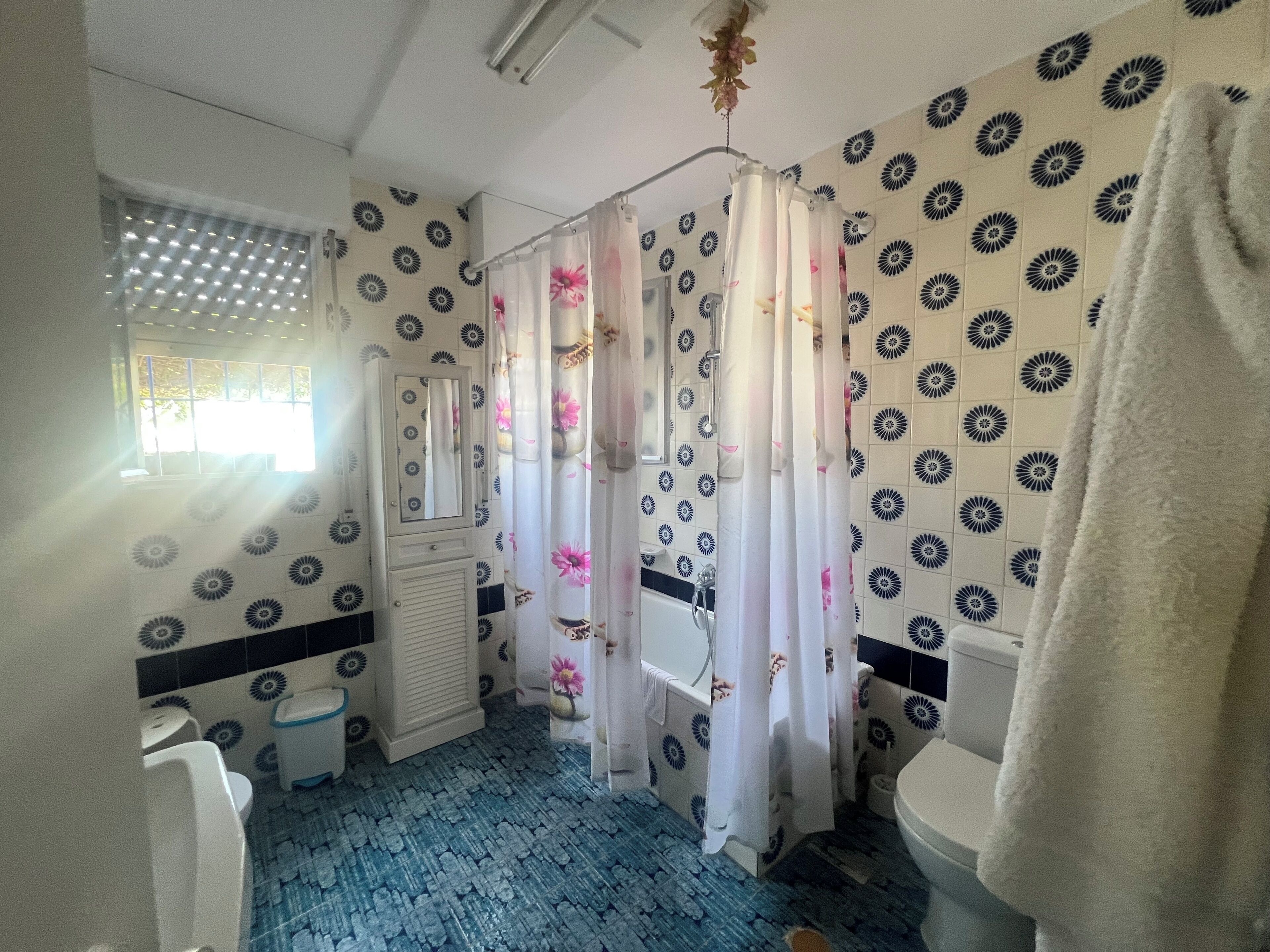 A bathroom with a shower curtain, a toilet, a sink, and a mirror.