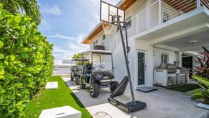 Uma casa moderna com cesta de basquete, carrinho de golfe e espaço para churrasco.
