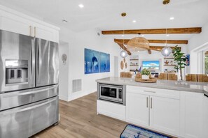 A modern kitchen with stainless steel appliances, a wooden ceiling, and decorative wall art. - Private Beach, Waterfront, Islamorada, Island house with a pool & a boat dock (Islamorada)