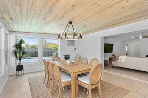 A dining area with a wooden table and chairs, a chandelier, and a potted plant. - Coastal Cactus- Pool+Pickleball+Putting Green+Shuffleboard! (Manatee County)