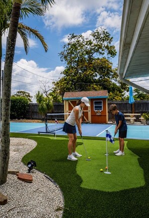 A residential area with a swimming pool, a tennis court, and a small wooden structure. - Coastal Cactus- Pool+Pickleball+Putting Green+Shuffleboard! (Manatee County)