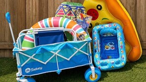 A blue and white baby stroller with a canopy, a colorful beach ball, and an inflatable dinosaur toy against a wooden fence backdrop. - Coastal Cactus- Pool+Pickleball+Putting Green+Shuffleboard! (Manatee County)