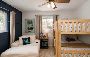 A bedroom with bunk beds, a ceiling fan, a poster on the wall, and a small bedside table with a lamp. - Coastal Cactus- Pool+Pickleball+Putting Green+Shuffleboard! (Manatee County)