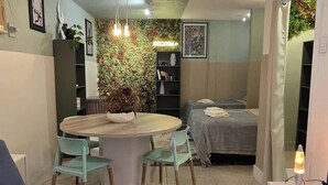 A compact living space with a dining area, a sofa, a bed, and a small kitchenette. - A cozy studio apartment with the charm of an open-concept design that feels like home. (Joinville)