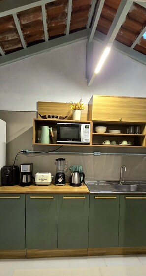 Eine Küche mit Mikrowelle, Toaster, Mixer und Kaffeemaschine auf der Arbeitsfläche.
