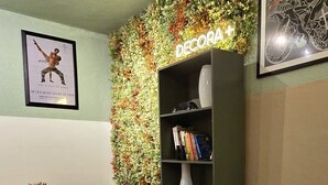 A bedroom with a bed, a desk, a bookshelf, a wall-mounted plant, and a framed picture. - A cozy studio apartment with the charm of an open-concept design that feels like home. (Joinville)