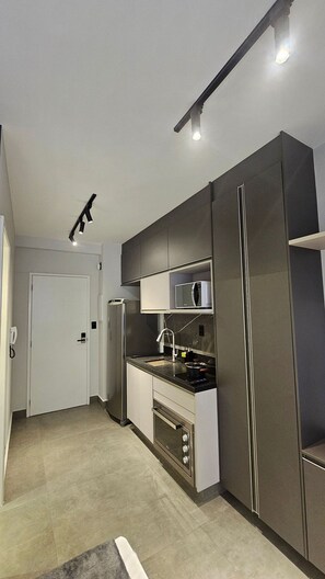A modern kitchen with built-in appliances, a microwave, and a stainless steel refrigerator. - Cond. Constantino Campo Belo NR (São Paulo)