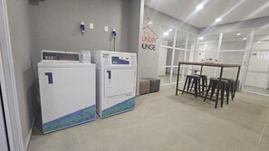 Un cuarto de lavandería con dos lavadoras, una mesa con sillas y un letrero que dice 'The Laundry Lounge'.