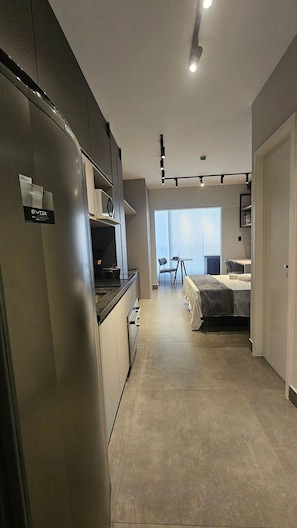 Ein kleines Hotelzimmer mit Küchenzeile, einem Bett, einem Tisch und einem Stuhl.
