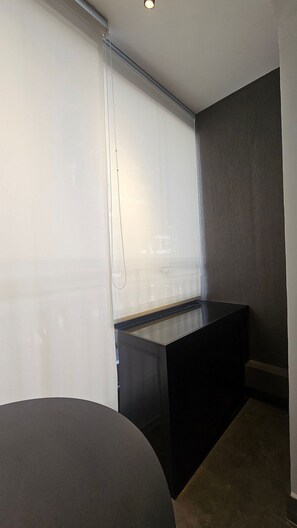 Ein Zimmer mit einem großen Fenster, einer dunklen Bank und einem teilweisen Blick auf ein Bett.