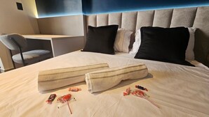 Ein Hotelzimmer mit Bett, zwei Kissen, einem Sessel und einem Schreibtisch.