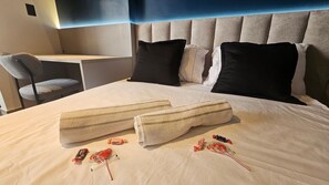 Ein Hotelzimmer mit Bett, zwei Kissen, einem Sessel und einem Schreibtisch.