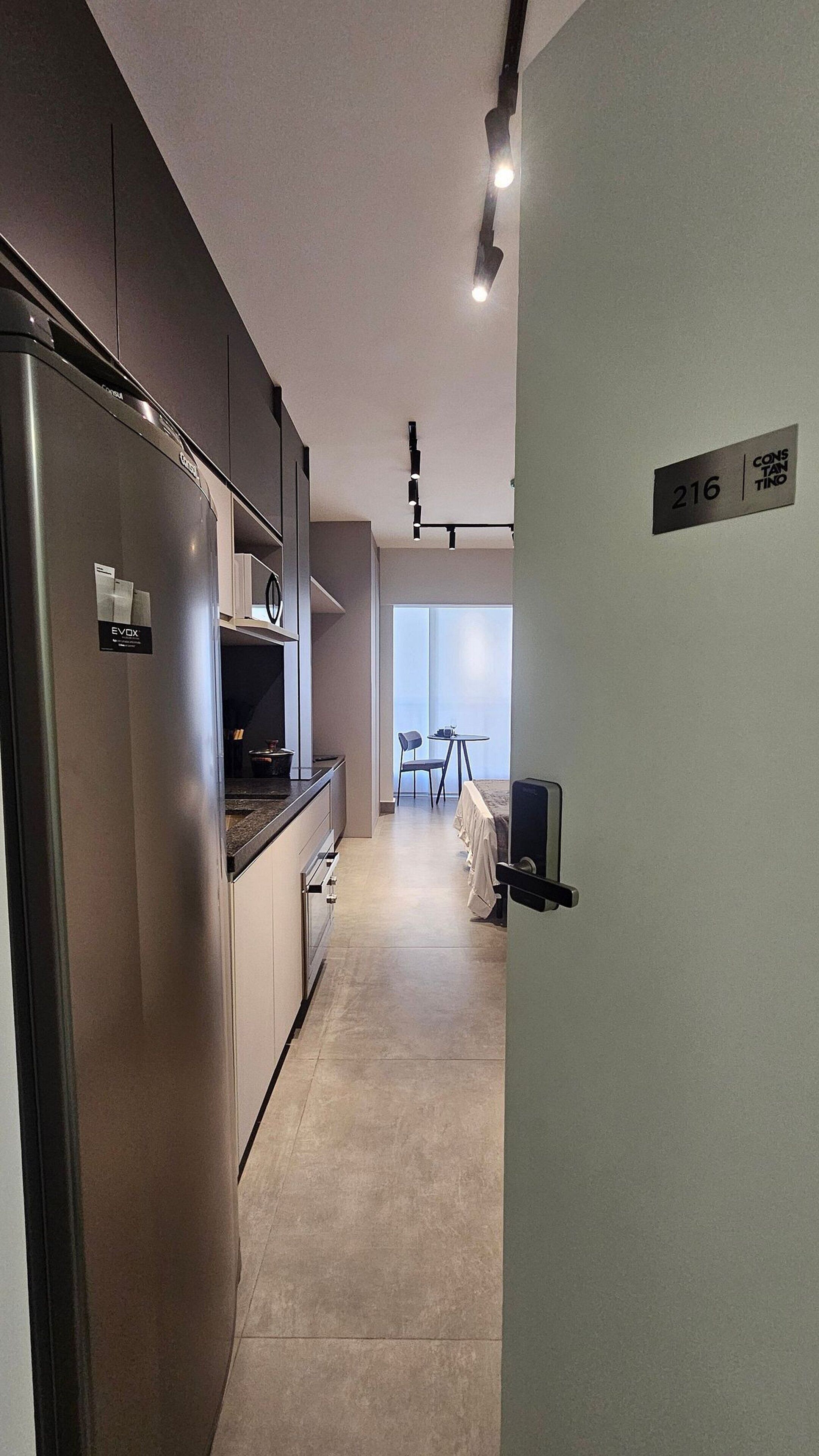 Uma cozinha moderna com frigorífico embutido, área de refeições com mesa e cadeiras, e varanda com vista.