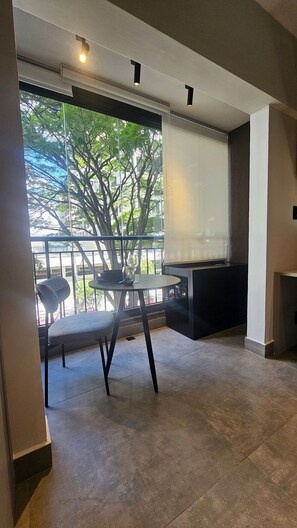 A modern room with a large window, a table, and a chair. - Cond. Constantino Campo Belo NR (São Paulo)