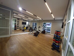 Une salle de sport équipée de matériel d’exercice, dotée d’un mur avec des miroirs et offrant une vue sur l’extérieur.