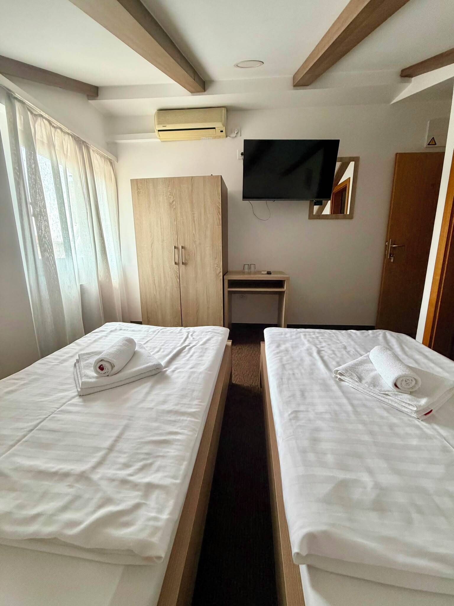 Habitación de hotel con dos camas, televisión, armario y escritorio.