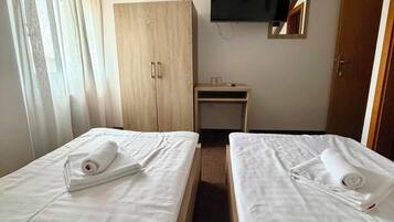 Habitación de hotel con dos camas, televisión, armario y escritorio.