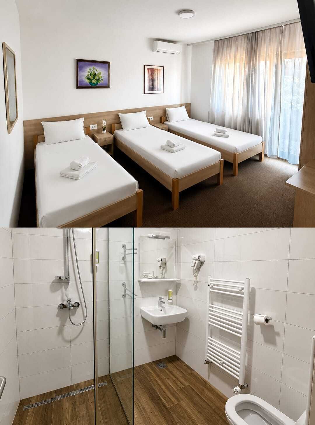 Habitación de hotel con dos camas, baño con ducha, lavamanos e inodoro.