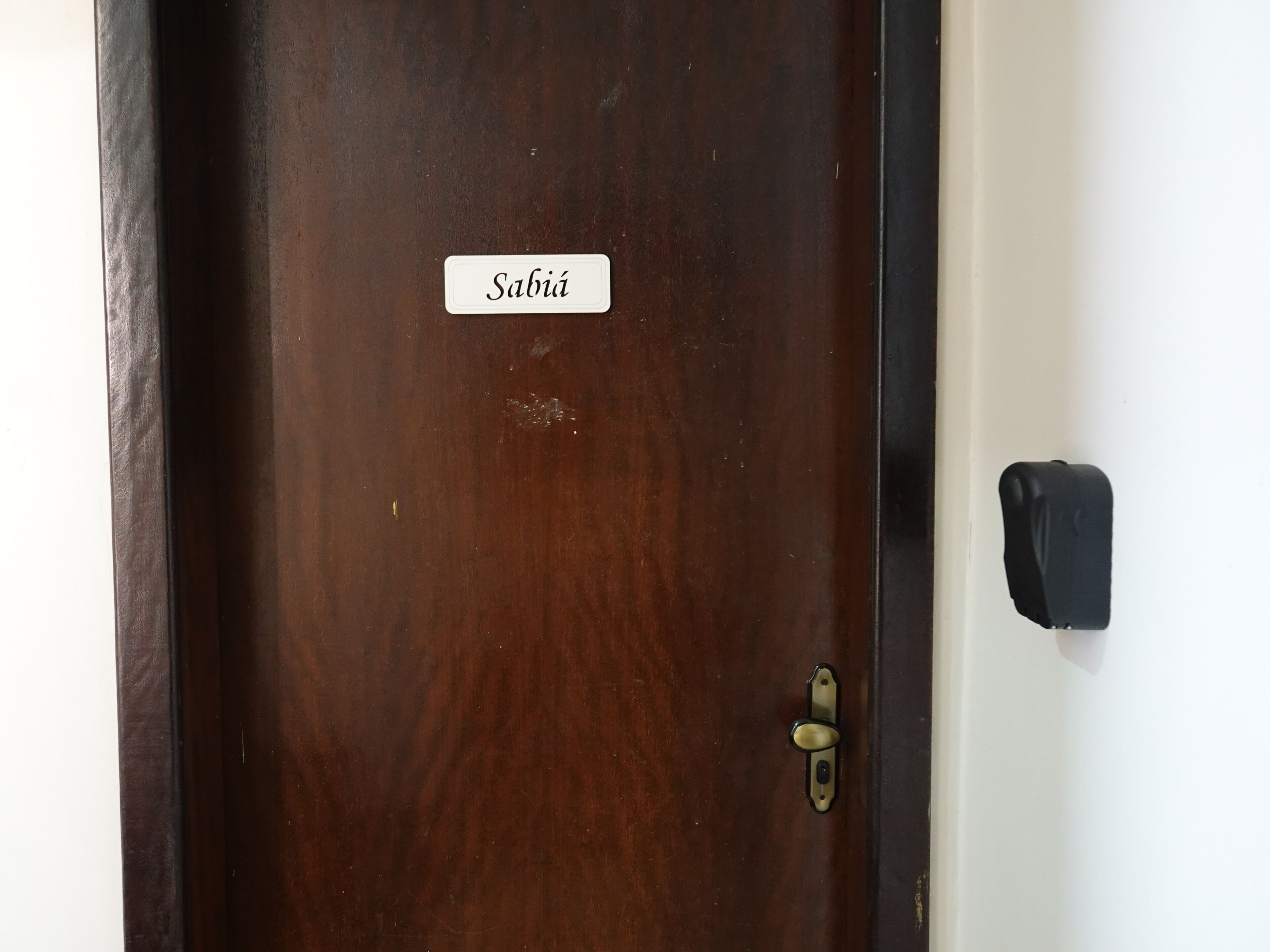 Uma porta de madeira com fechadura de latão e uma placa que diz 'Sabiá'.